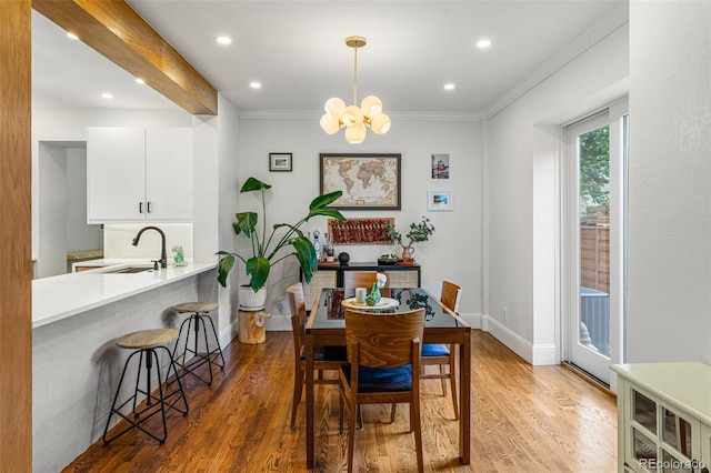 dining area with a chandelier, recessed lighting, wood finished floors, baseboards, and crown molding