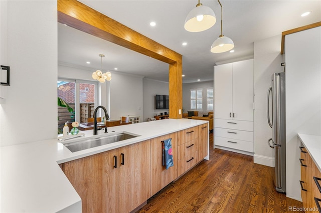 kitchen featuring dark wood-style flooring, a sink, light countertops, freestanding refrigerator, and modern cabinets