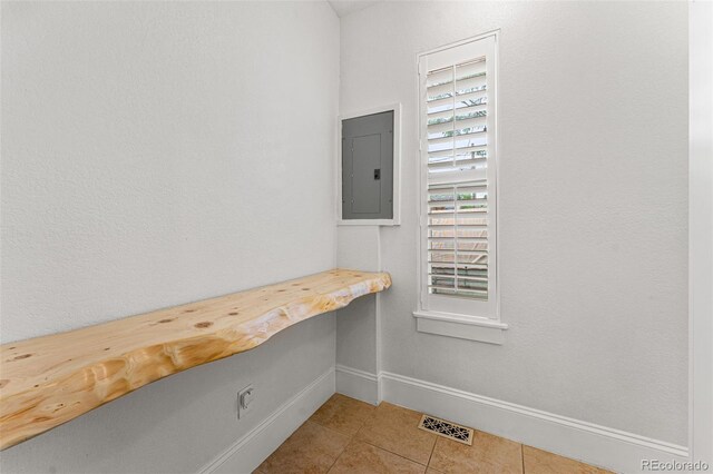 interior details featuring baseboards, electric panel, visible vents, and built in desk