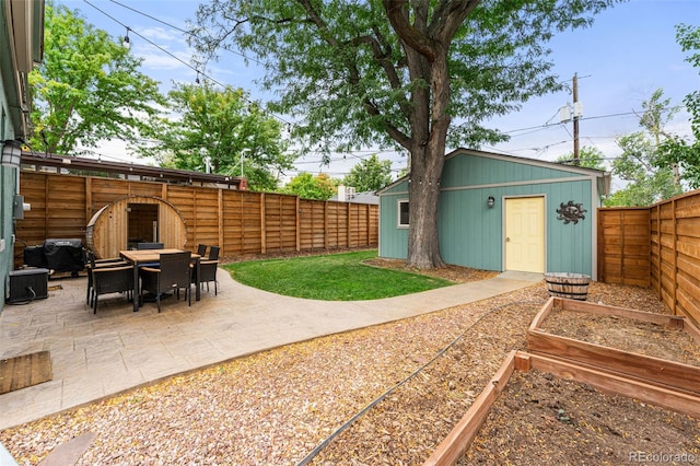 view of yard featuring a garden, a fenced backyard, outdoor dining area, an outdoor structure, and a patio area