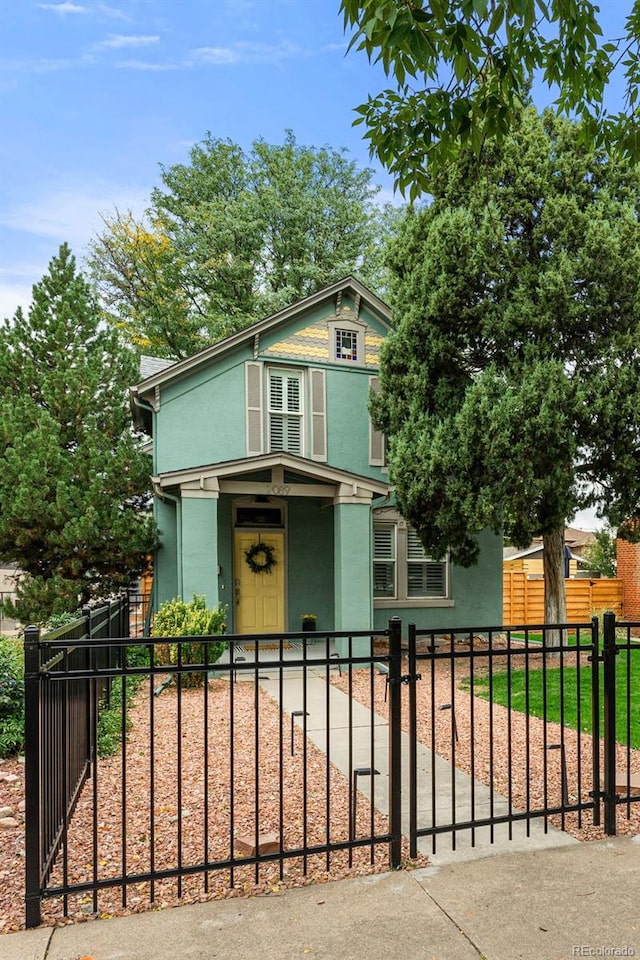 victorian home featuring a fenced front yard and stucco siding