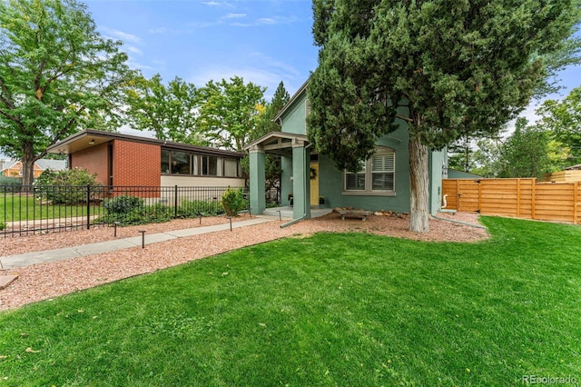 view of front facade with stucco siding, fence, a front lawn, and brick siding