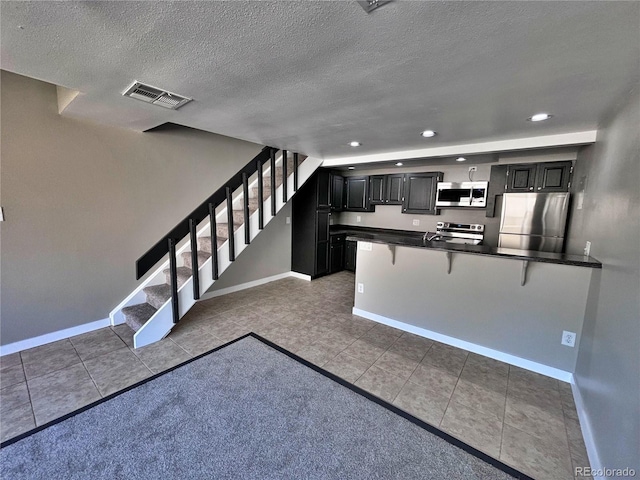 371 S Estes St Unit 10, Lakewood, CO 80226 - kitchen with appliances with stainless steel finishes, a kitchen breakfast bar, dark cabinetry, baseboards, and dark countertops
