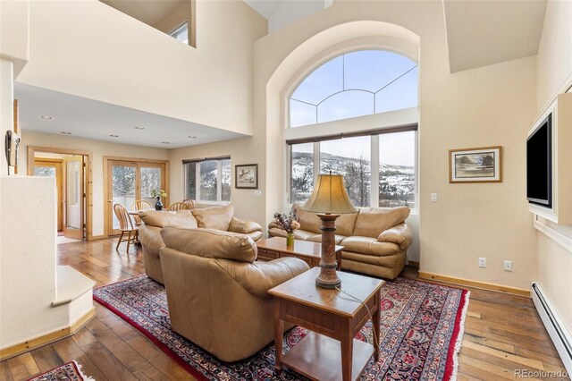 11 Hackamore Rd Unit B, Edwards, CO 81632 - living room featuring a high ceiling, wood-type flooring, baseboards, and a baseboard radiator