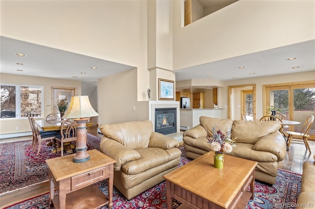 11 Hackamore Rd Unit B, Edwards, CO 81632 - living area featuring wood finished floors, a high ceiling, recessed lighting, a glass covered fireplace, and a baseboard heating unit