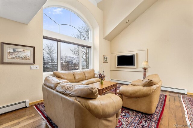 11 Hackamore Rd Unit B, Edwards, CO 81632 - living room with a baseboard radiator, baseboard heating, a high ceiling, and hardwood / wood-style flooring