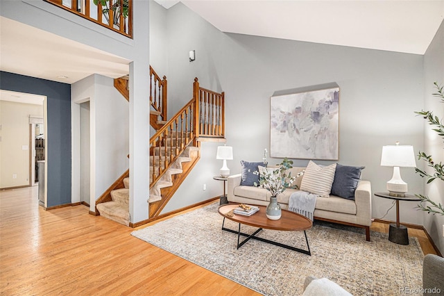 living room with high vaulted ceiling, baseboards, wood finished floors, and stairs
