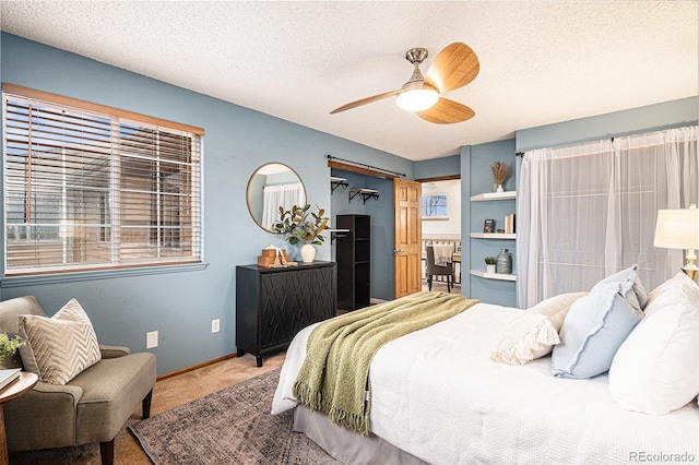 carpeted bedroom featuring a textured ceiling, ceiling fan, and baseboards
