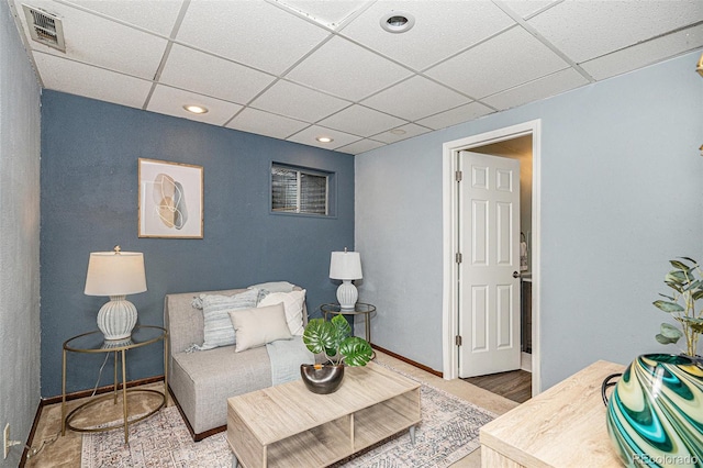 living area with a paneled ceiling and baseboards