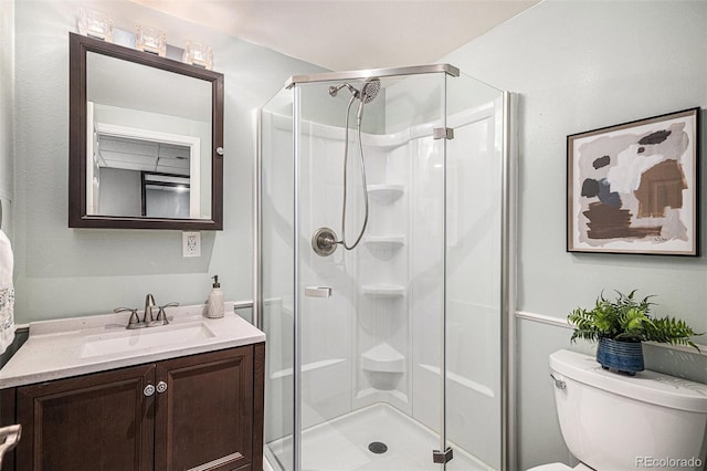 bathroom with a stall shower, toilet, and vanity