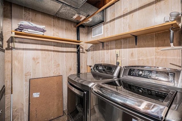 laundry room featuring separate washer and dryer and wooden walls