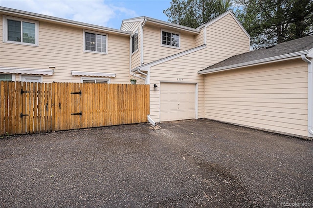 view of side of home featuring fence, asphalt driveway, and a garage