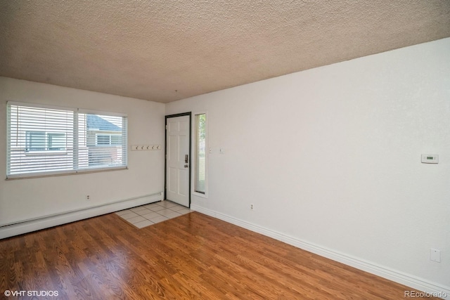 unfurnished room featuring a textured ceiling, a baseboard radiator, and light hardwood / wood-style flooring