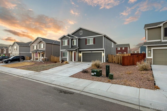 traditional-style house featuring concrete driveway, an attached garage, fence, and a residential view