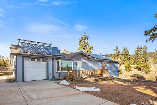 view of front facade with a garage, solar panels, and concrete driveway