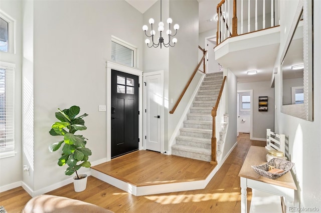 entryway featuring hardwood / wood-style floors, a towering ceiling, and an inviting chandelier