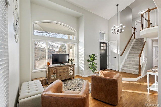 living room featuring light hardwood / wood-style floors, a high ceiling, and a chandelier