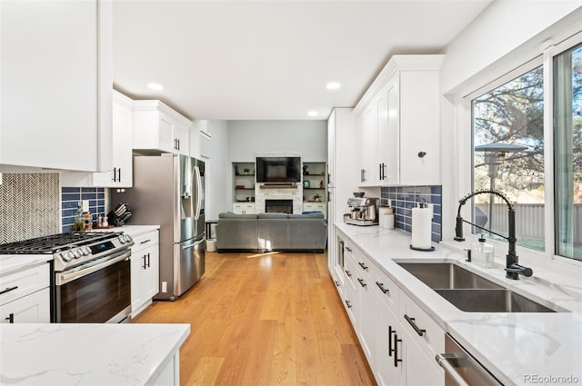 kitchen featuring light stone countertops, sink, white cabinetry, and stainless steel appliances