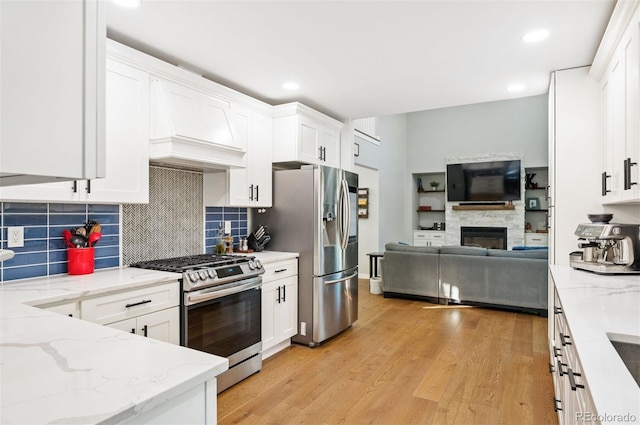 kitchen featuring stainless steel appliances, white cabinetry, and light stone counters