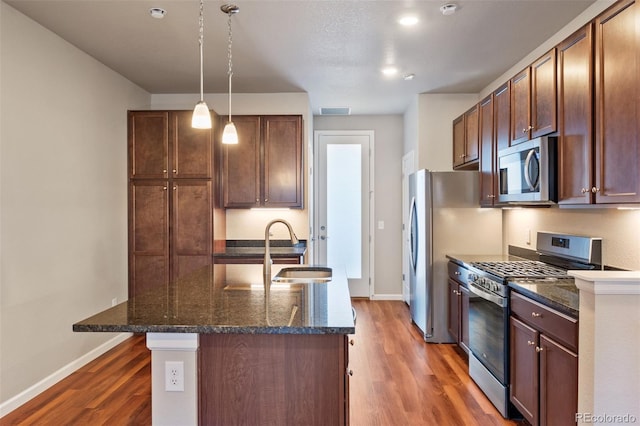 kitchen featuring appliances with stainless steel finishes, dark hardwood / wood-style floors, a center island with sink, and sink