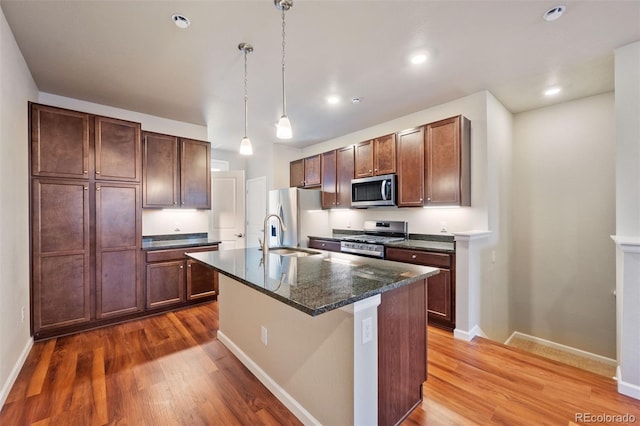 kitchen featuring appliances with stainless steel finishes, dark hardwood / wood-style flooring, a kitchen island with sink, and sink