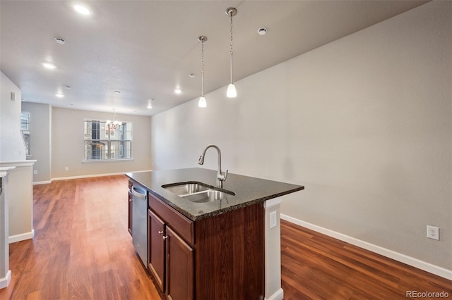 kitchen with sink, dark hardwood / wood-style flooring, stainless steel dishwasher, decorative light fixtures, and a center island with sink