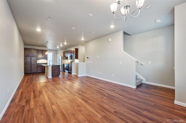 unfurnished living room featuring dark hardwood / wood-style flooring, an inviting chandelier, and sink