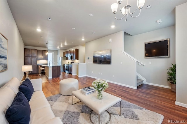 living room with hardwood / wood-style floors, an inviting chandelier, and sink