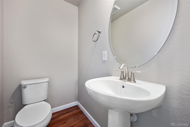 bathroom with hardwood / wood-style flooring, toilet, and sink