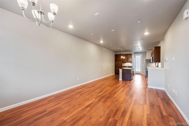 unfurnished living room featuring sink, dark wood-type flooring, and a chandelier