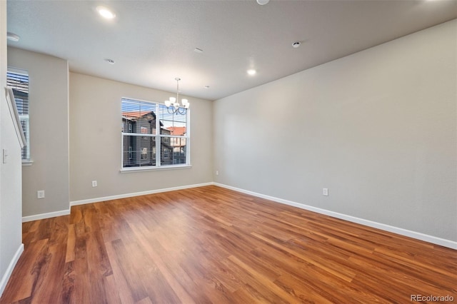 empty room featuring hardwood / wood-style flooring and a notable chandelier