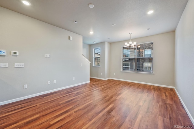 spare room featuring hardwood / wood-style flooring, a textured ceiling, and an inviting chandelier