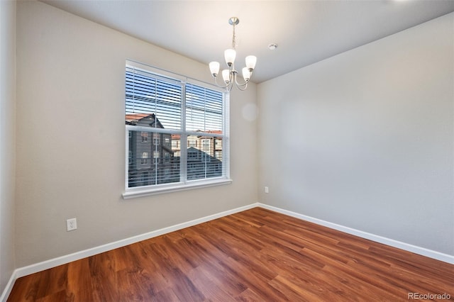 spare room with hardwood / wood-style floors and a chandelier