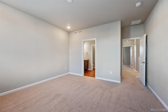 unfurnished bedroom with light carpet and connected bathroom