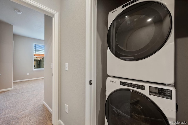 clothes washing area featuring stacked washer / drying machine and light colored carpet