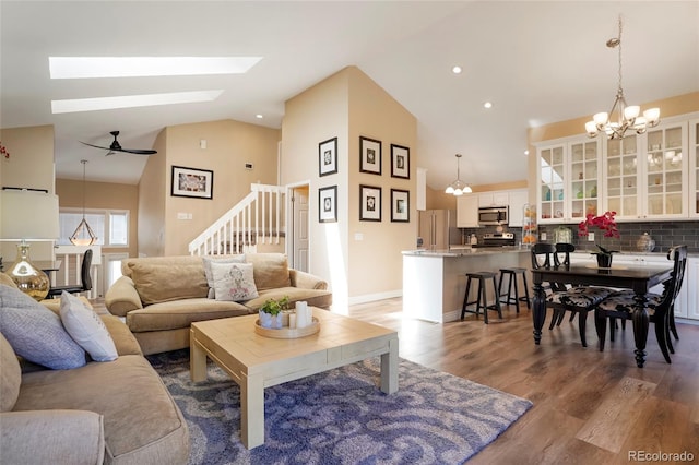 living room with high vaulted ceiling, recessed lighting, wood finished floors, baseboards, and stairway