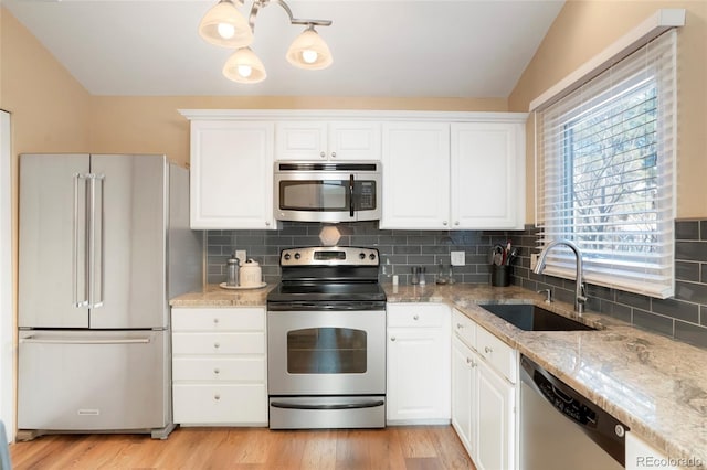 kitchen with appliances with stainless steel finishes, white cabinets, a sink, and light stone countertops