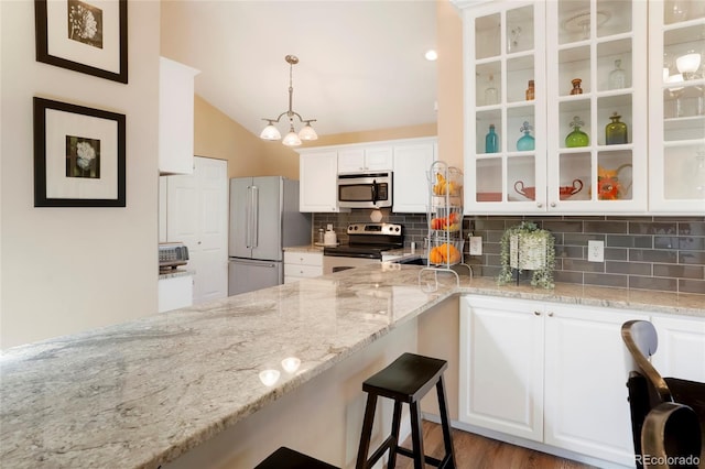 kitchen featuring stainless steel appliances, white cabinets, hanging light fixtures, and light stone counters