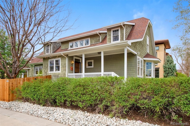 traditional home featuring fence and covered porch