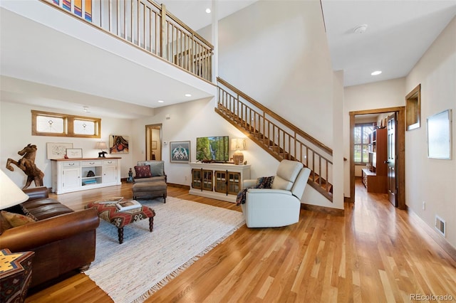 living area featuring light wood-style floors, stairs, and visible vents