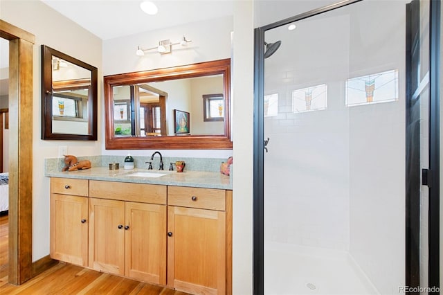 bathroom featuring wood finished floors, a stall shower, and vanity