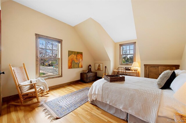 bedroom featuring baseboards, lofted ceiling, and wood finished floors