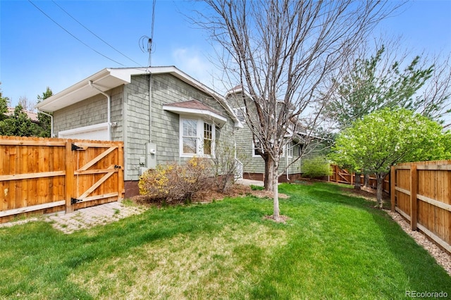 view of side of home featuring a lawn, a fenced backyard, and a gate