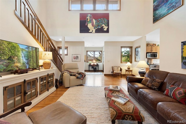 living room with wood finished floors, a high ceiling, and stairway