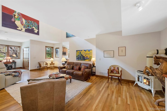 living area with baseboards, a wood stove, and light wood-style floors