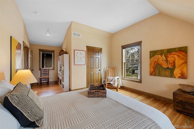 bedroom with wood finished floors, baseboards, lofted ceiling, and visible vents