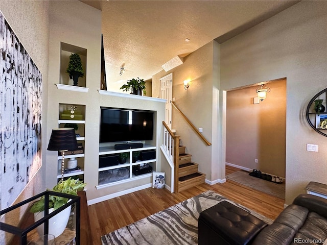 living room featuring built in features, a textured ceiling, and hardwood / wood-style flooring