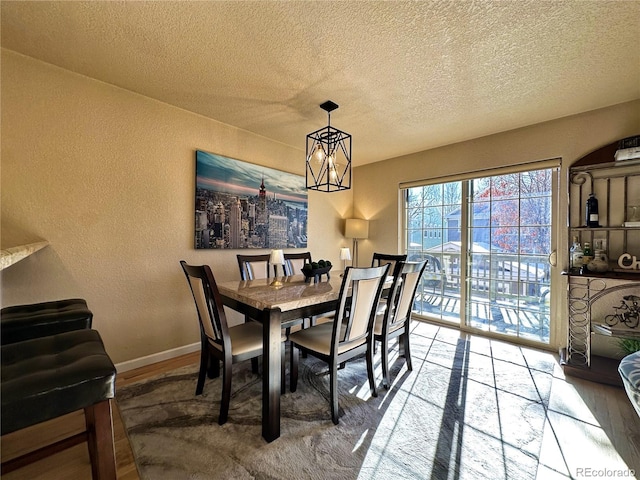 dining room featuring hardwood / wood-style floors, a textured ceiling, and an inviting chandelier