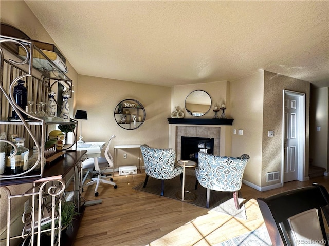 living room with hardwood / wood-style floors, a fireplace, and a textured ceiling