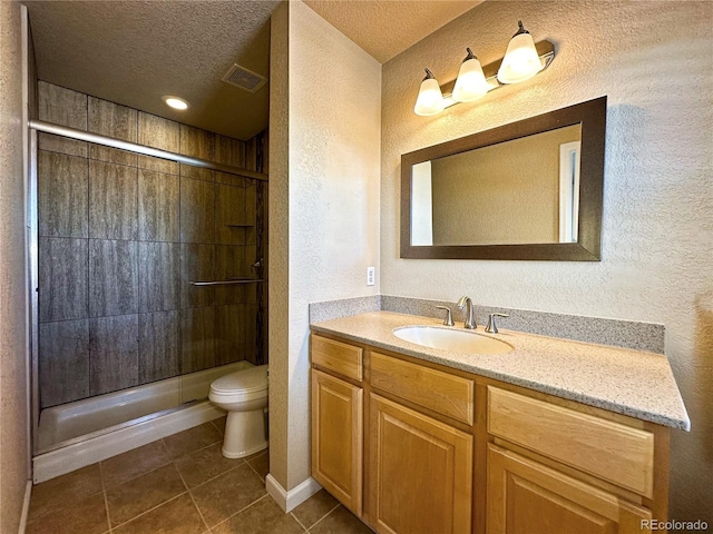 bathroom featuring a textured ceiling, vanity, a shower with door, tile patterned flooring, and toilet